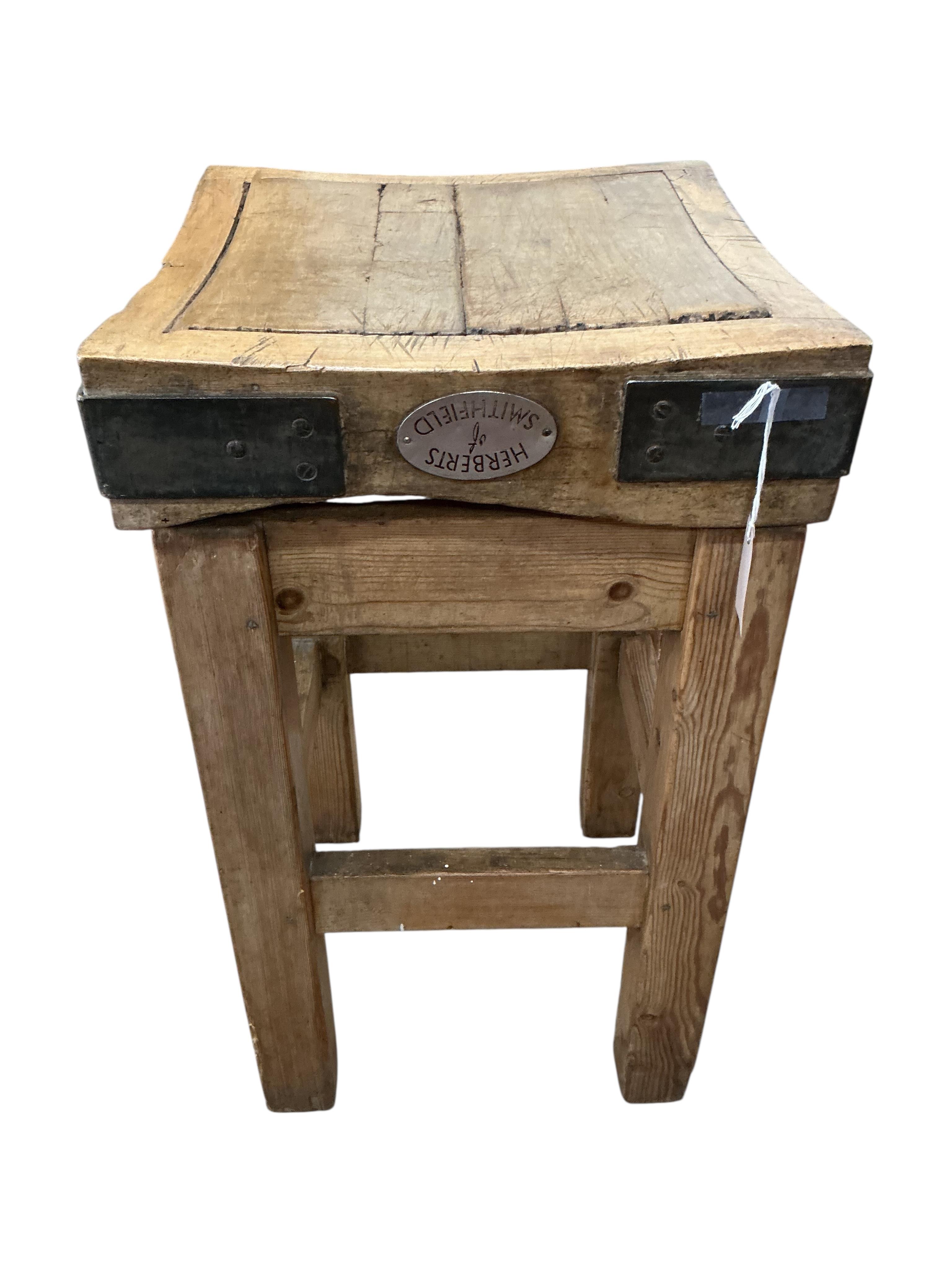 A small iron bound butcher’s block on stand bears metal plaque 